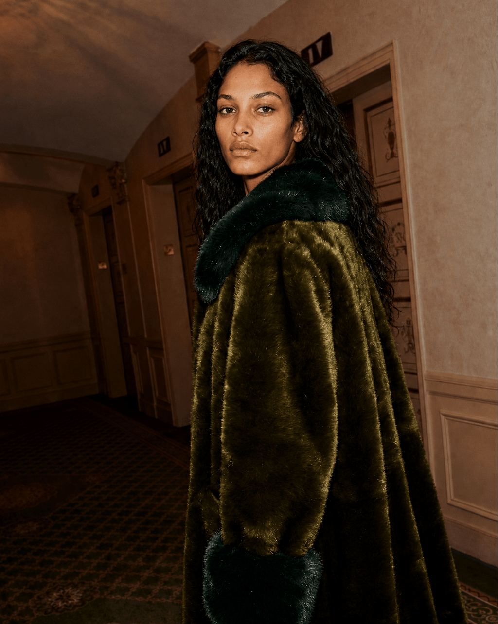 Le Junot Vert Émeraude worn with the collar up, green faux fur coat